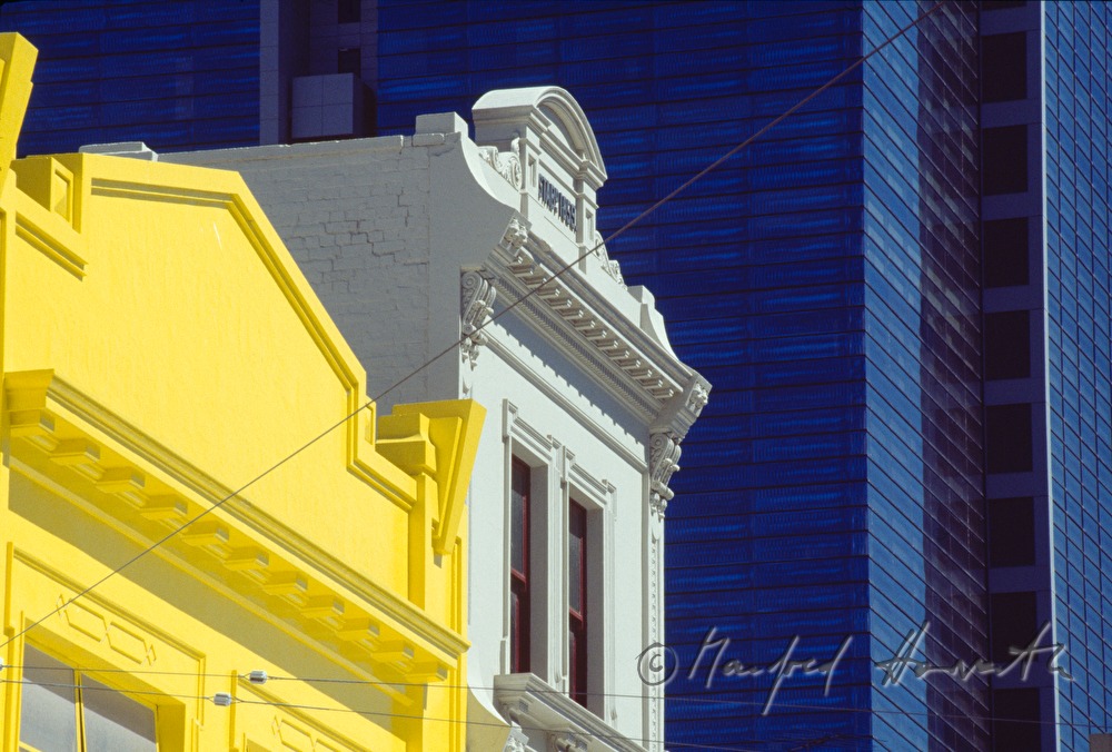 gelbes Wohnhaus vor Bürogebäude