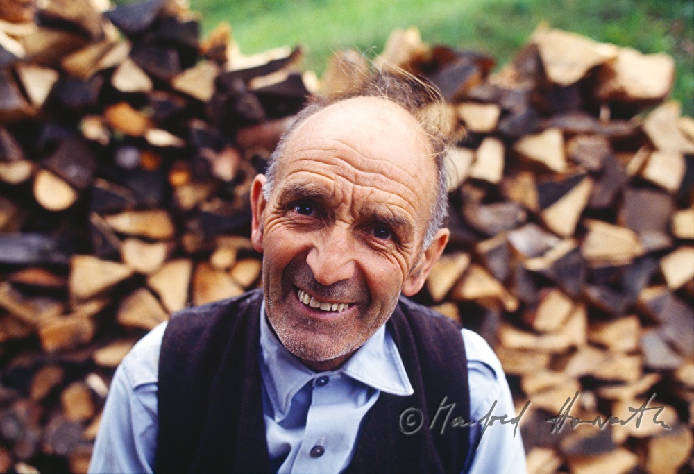 Bauer vor einem Holzstoss