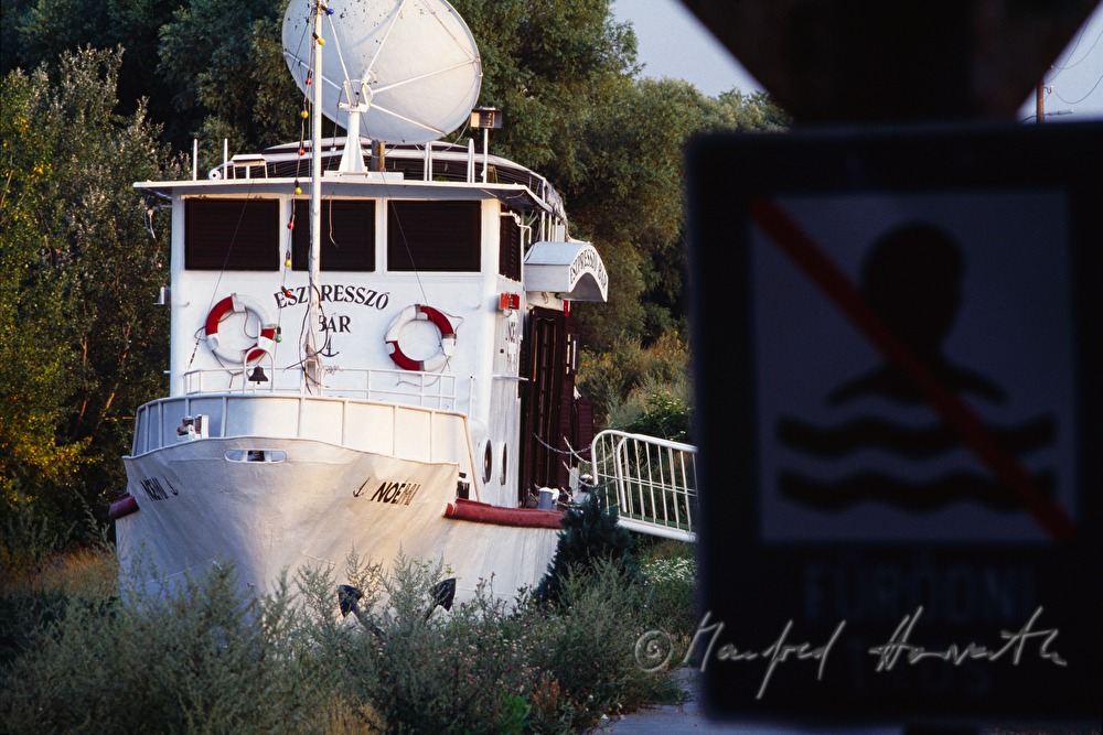 Restaurant-Schiff am Donau-Ufer und Schwimmverbots-Schild