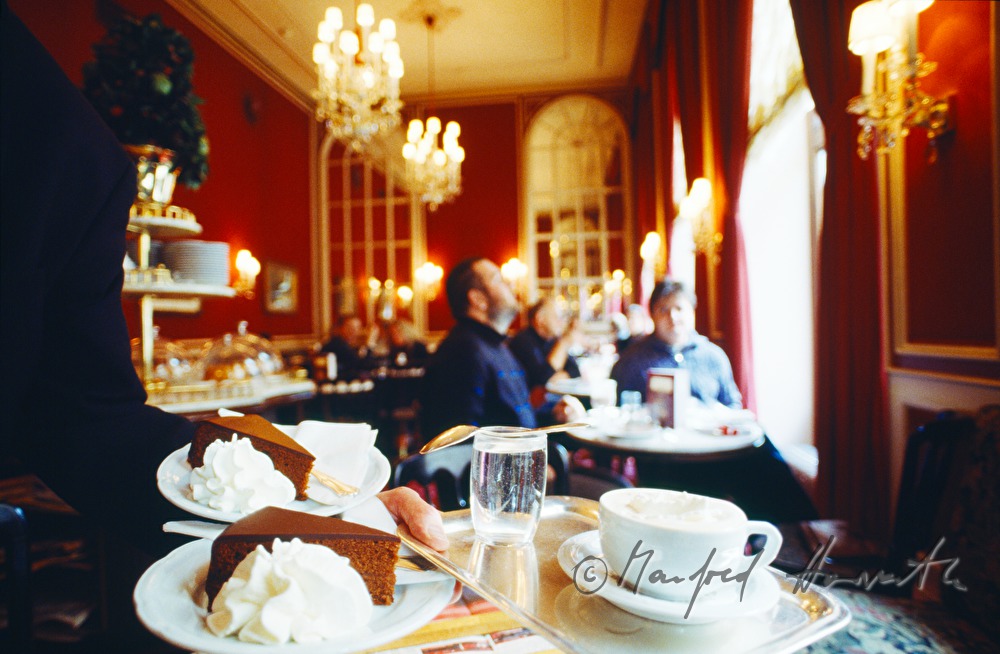 Ober serviert Sachertorte und Melange