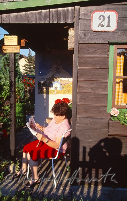 eine Frau liest vor ihrem Gartenhaus im Schrebergarten