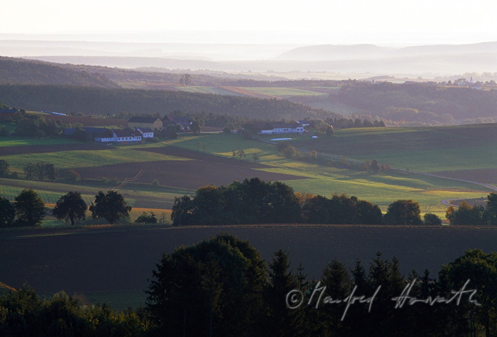 Bauernhöfe in hügeliger Landschaft
