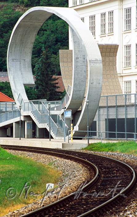 Eisenbahnschienen unf Füßgängerbrücke mit Betonskulptur 