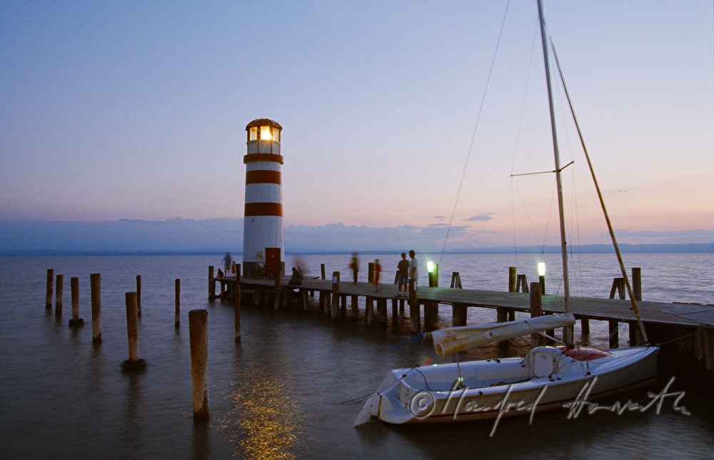 Leuchtturm, Segelboot und Steg mit Besuchern