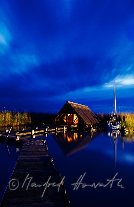 Seehütte mit Holzsteg und Segelboot