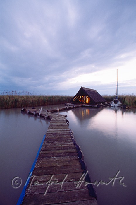 Seehütte mit Holzsteg und Segelboot