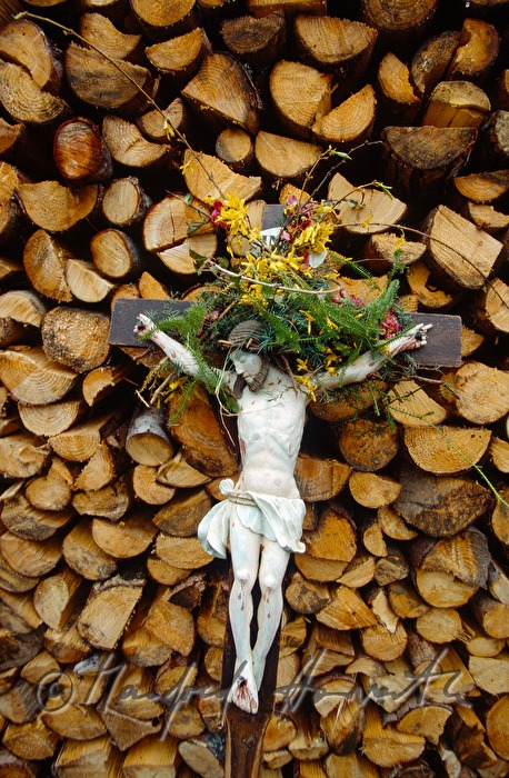 Kreuz eines Pilgers lehnt an Holzstoß