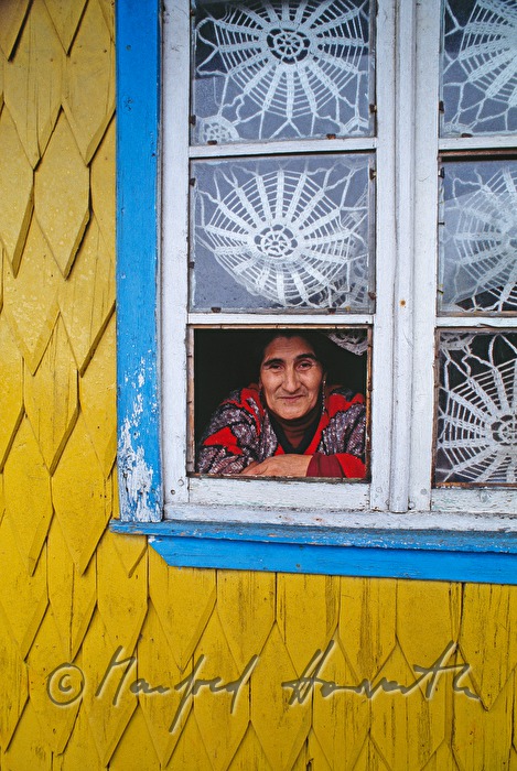 Frau schaut aus dem Fenster eines Schindelhaus