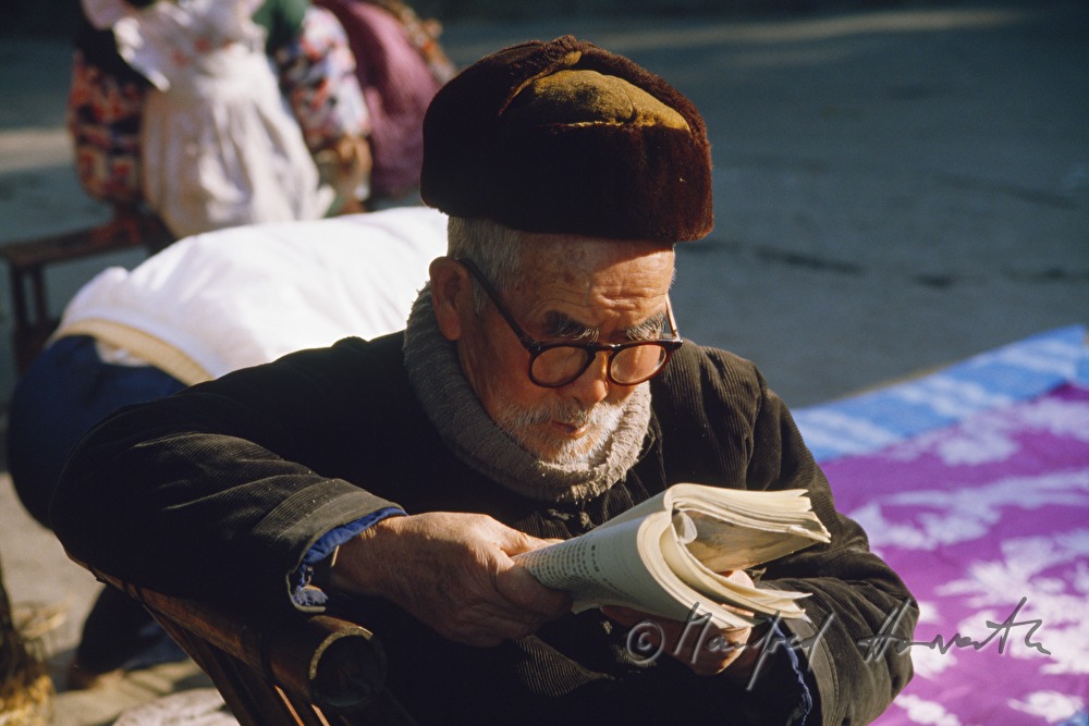 Mann liest ein Buch vor seinem Haus