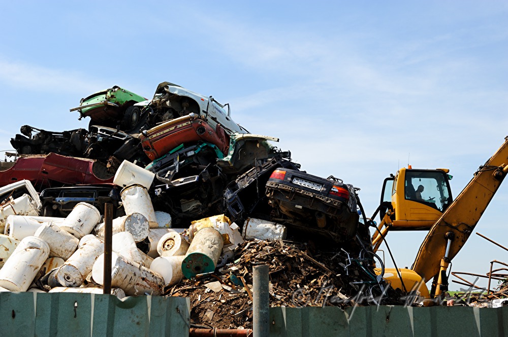 Bagger verladet Schrott auf Schrottplatz