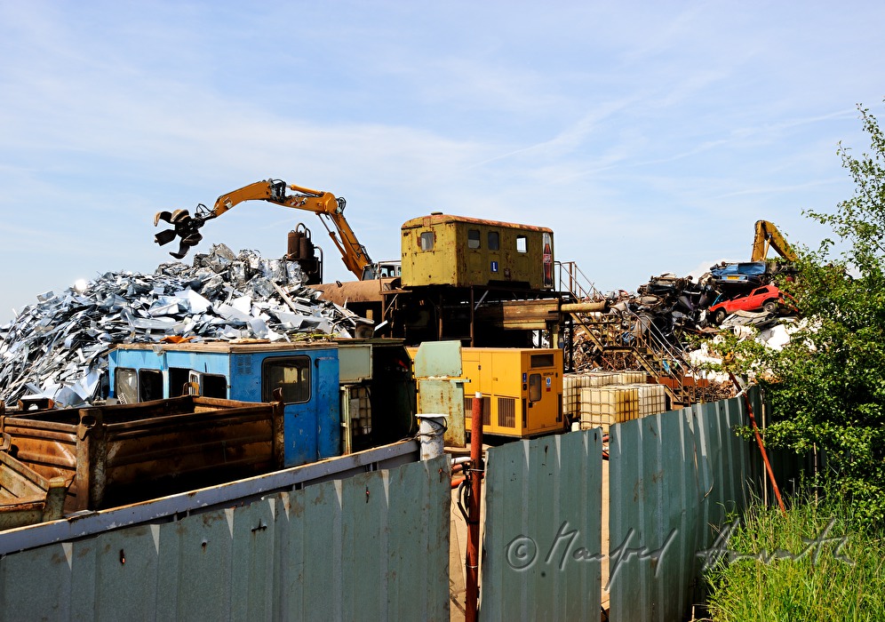 Bagger verladet Schrott auf Schrottplatz