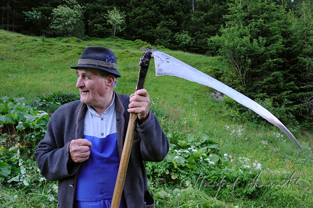 Bauer mäht seine Wiese mit der Sense