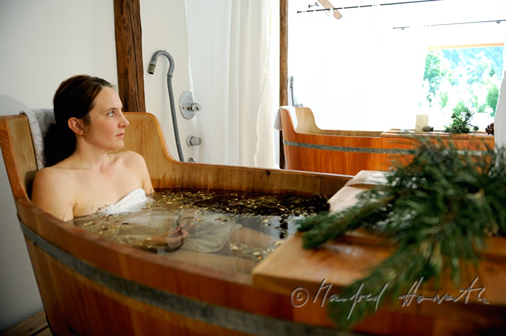 Frau nimmt ein Wellness-Latschen-Bad im Holzzuber