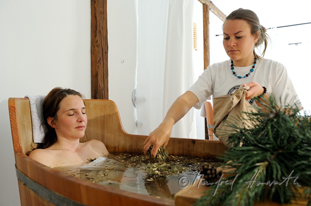 Frau nimmt ein Wellness-Latschen-Bad im Holzzuber