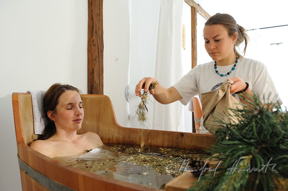 Frau nimmt ein Wellness-Latschen-Bad im Holzzuber