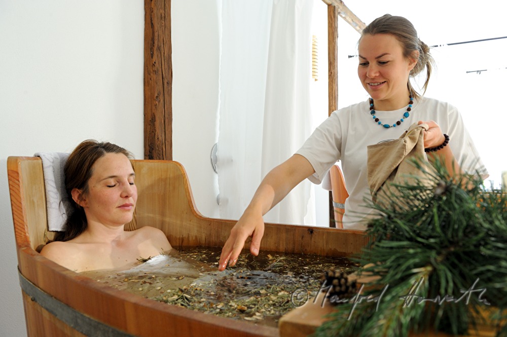 Frau nimmt ein Wellness-Latschen-Bad im Holzzuber