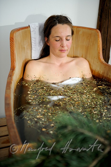 Frau nimmt ein Wellness-Latschen-Bad im Holzzuber