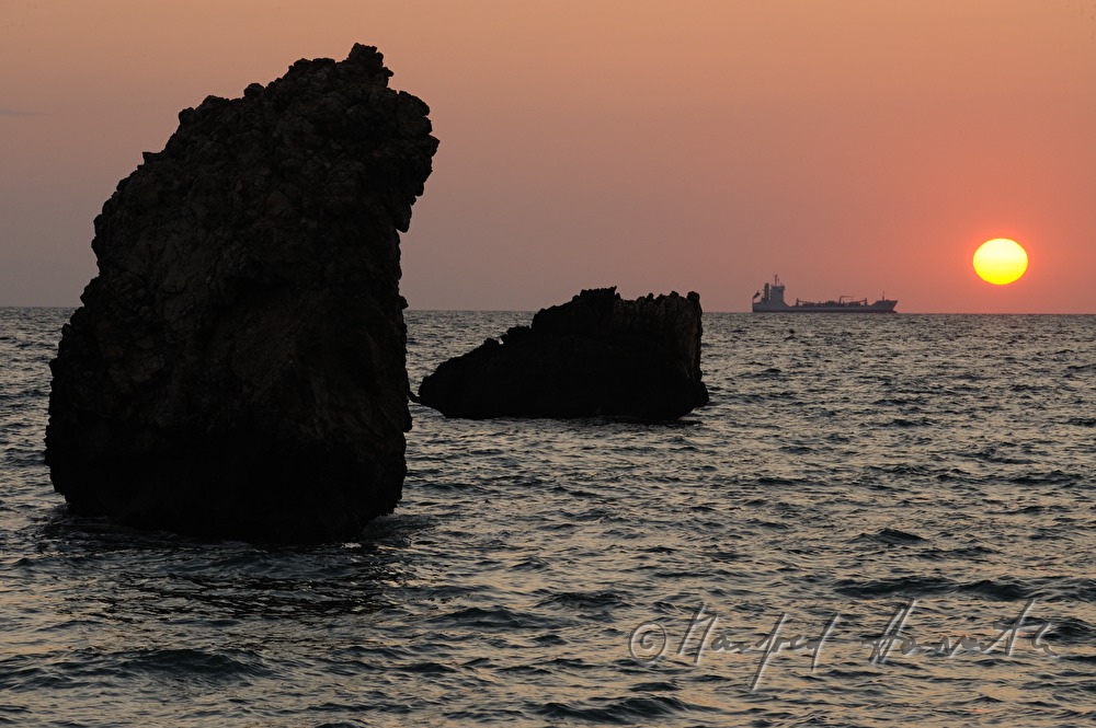 Containerschiff bei den Felsen am Strand