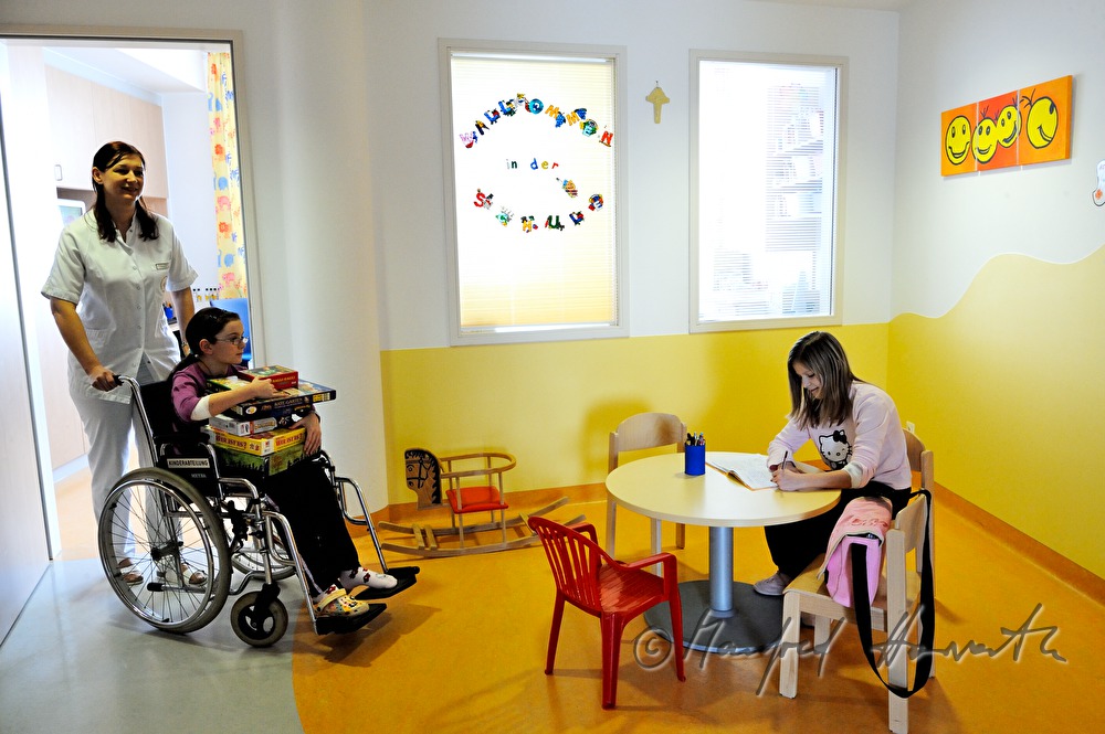 Krankenschwester schiebt Kind in das Spielzimmer