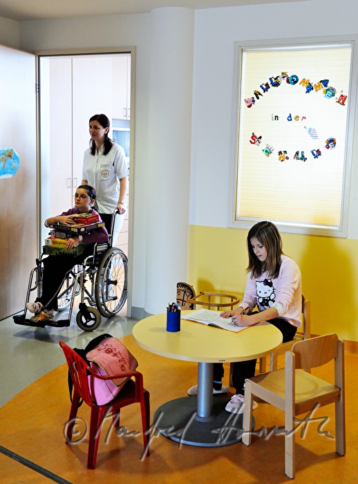 Krankenschwester schiebt Kind in das Spielzimmer