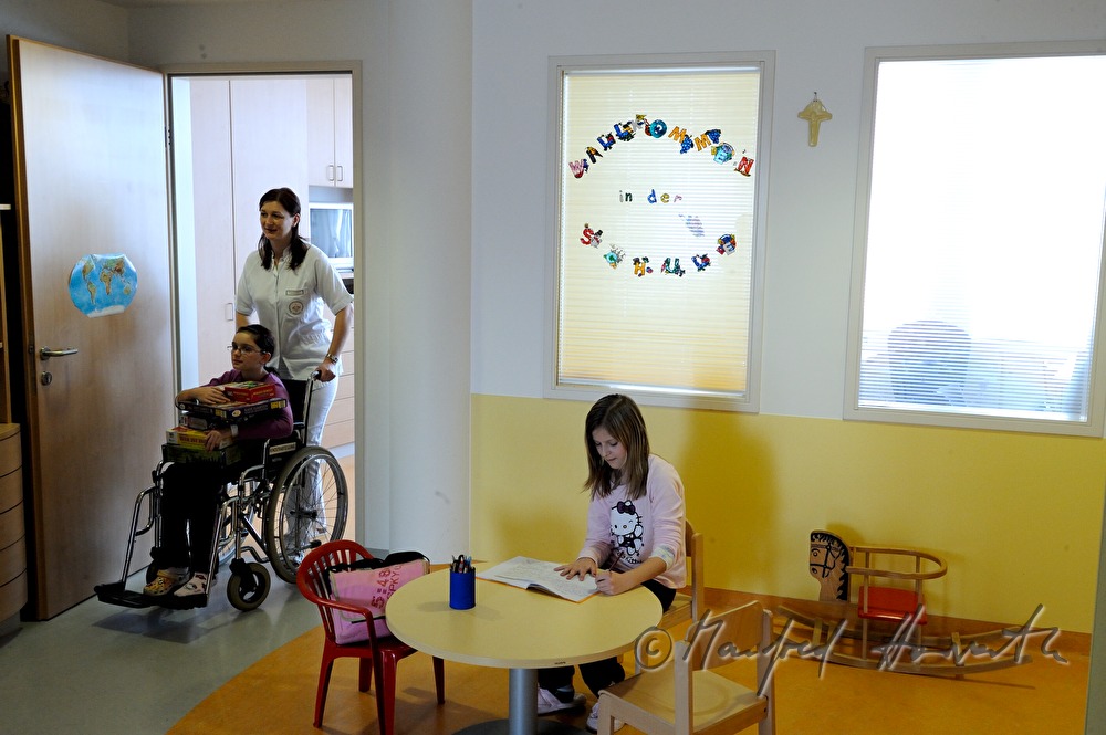 Krankenschwester schiebt Kind in das Spielzimmer