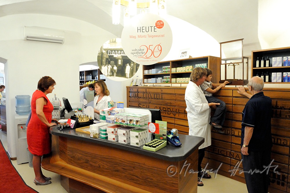 Apotheker zeigt seinen Kunden die alte Waage