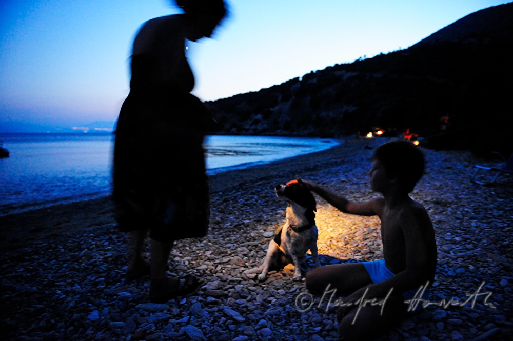 Kind und Frau spielen mit Hund am Strand