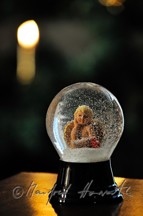 Schneekugel (mit Engel) vor einem Weihnachtsbaum