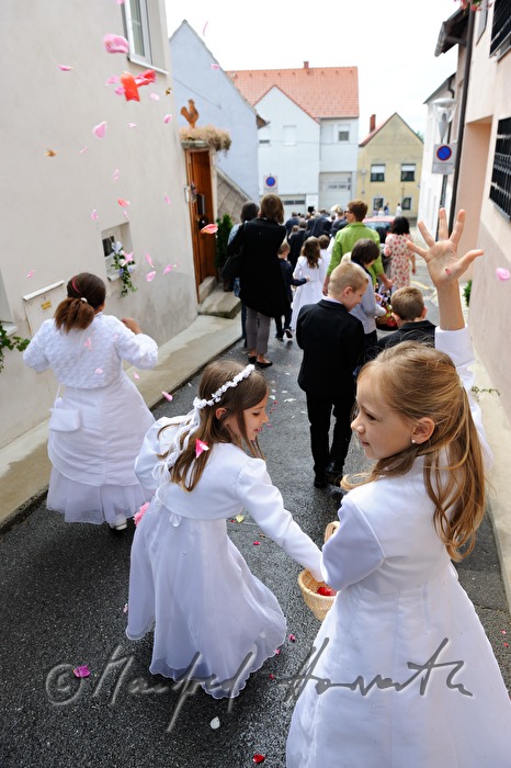 Kinder streuen Blütenblätter bei Fronleichnams-Prozession