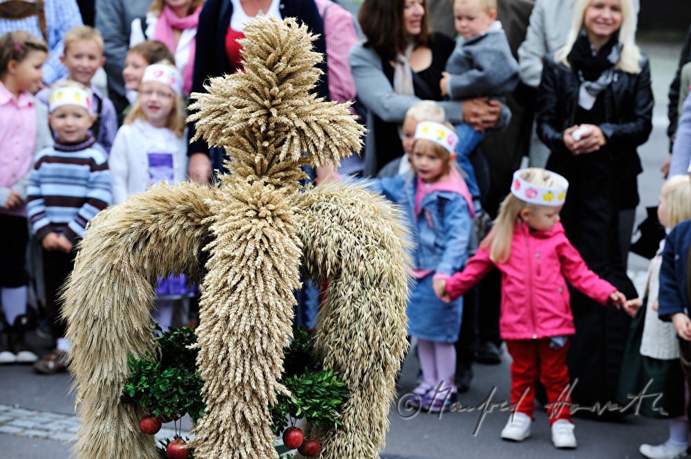 Kinder stehen im Kreis um die Erntedank-Krone