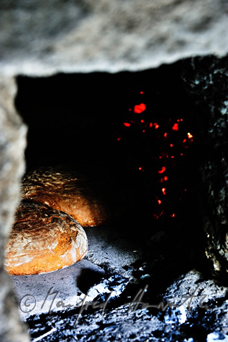 Backen von Holzofenbrot im feuerbetriebenen Backhaus