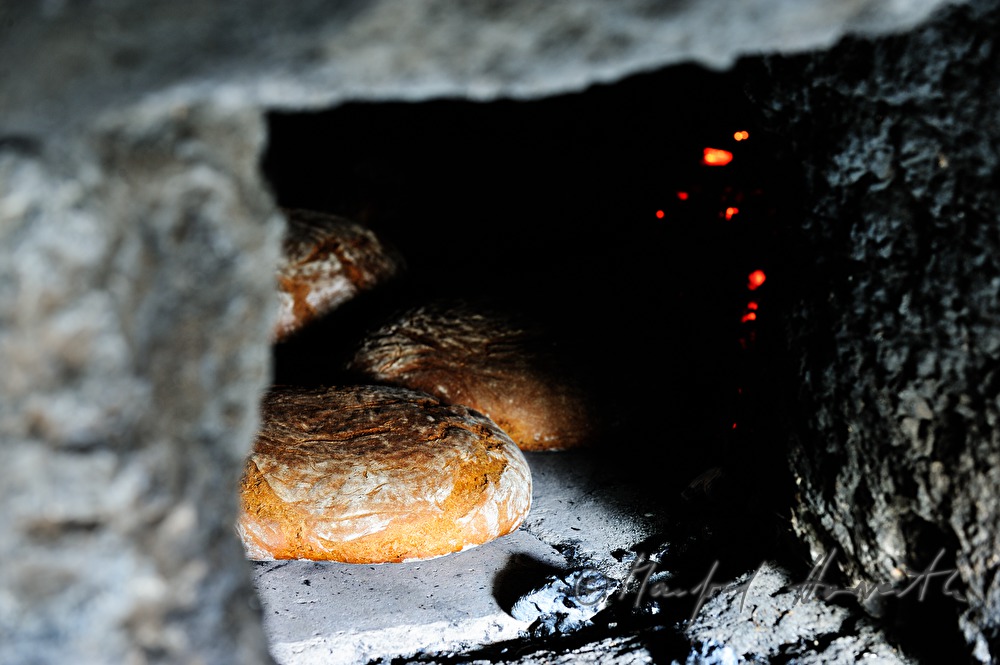 Backen von Holzofenbrot im feuerbetriebenen Backhaus