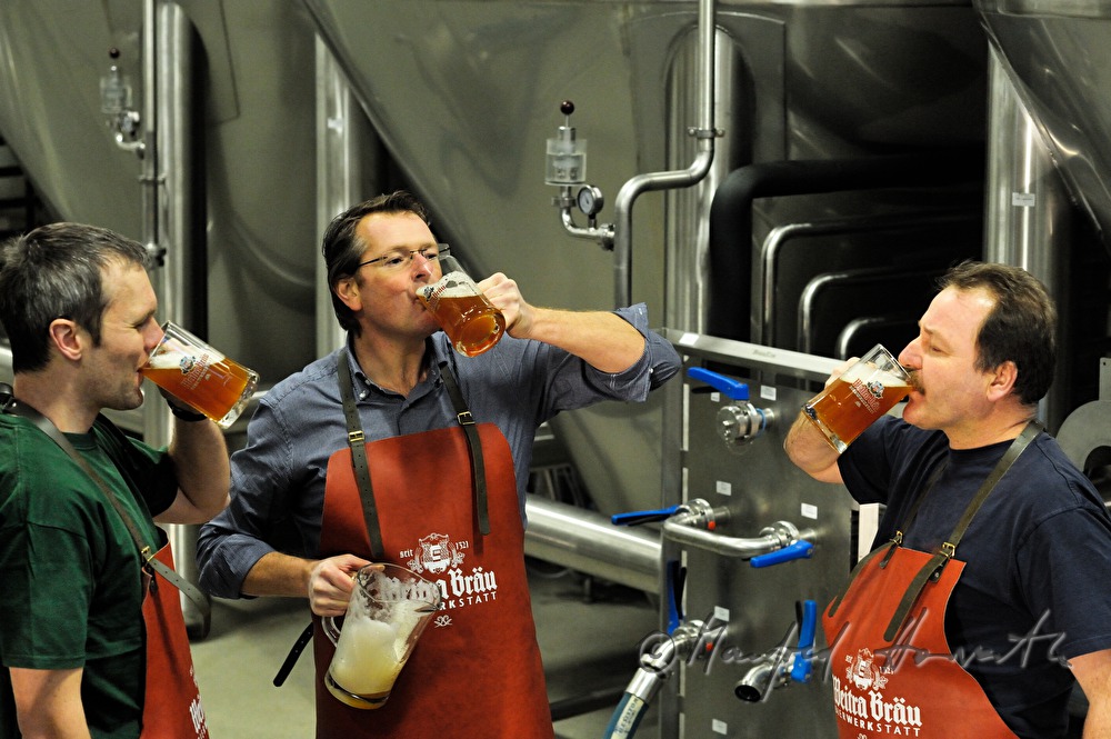 Braumeister und Arbeiter verkosten Bier im Keller