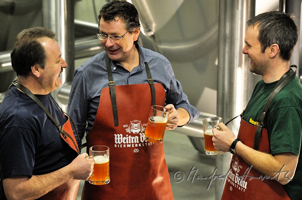 Braumeister und Arbeiter verkosten Bier im Keller