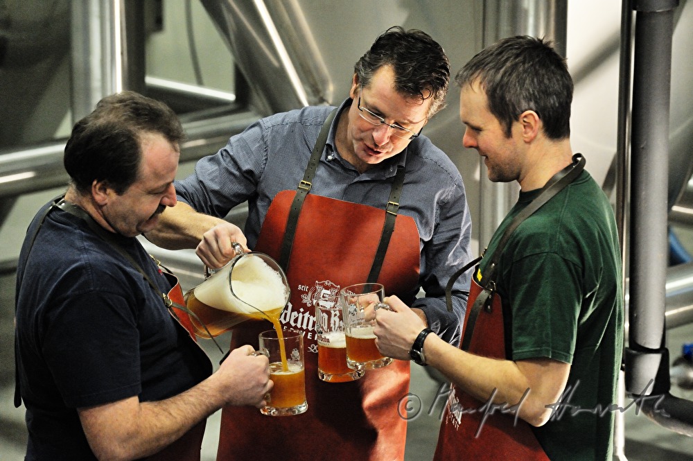 Braumeister und Arbeiter verkosten Bier im Keller