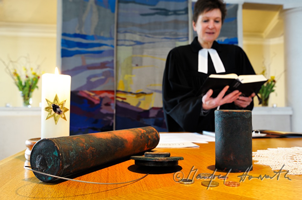 Pastorin beim Altar mit Zeitkapsel der Kirchturmspitze