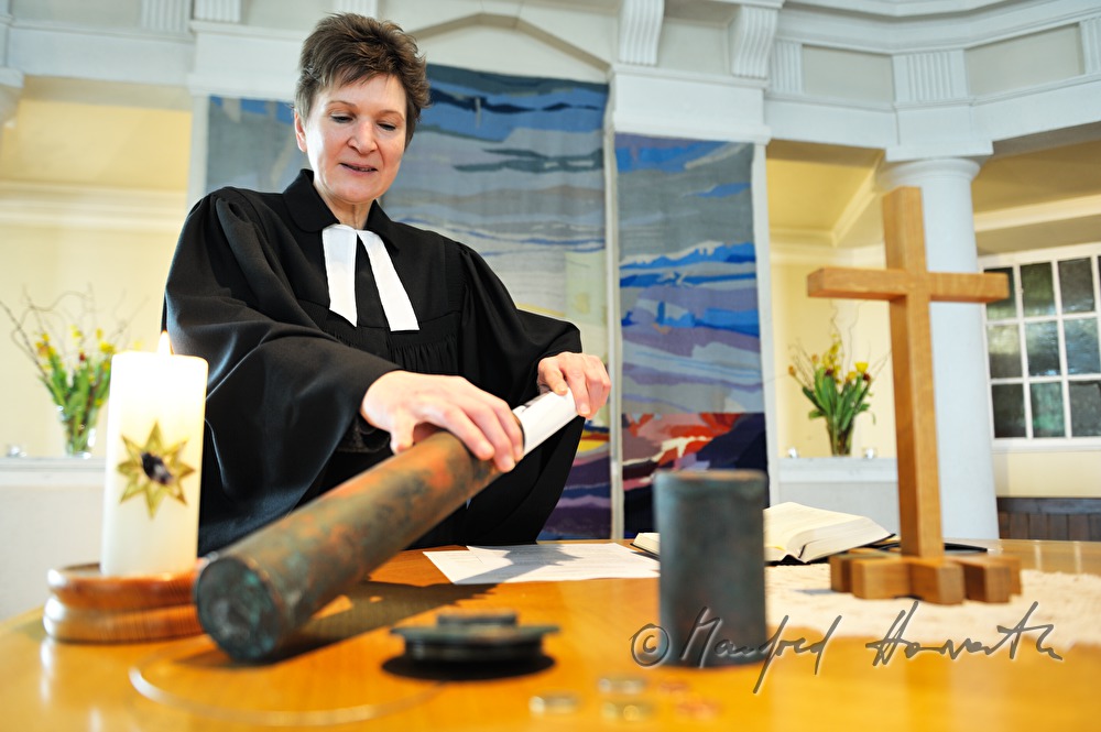 Pastorin beim Altar mit Zeitkapsel der Kirchturmspitze