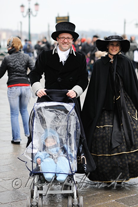 maskiertes Paar mit Kinderwagen auf dem Markusplatz
