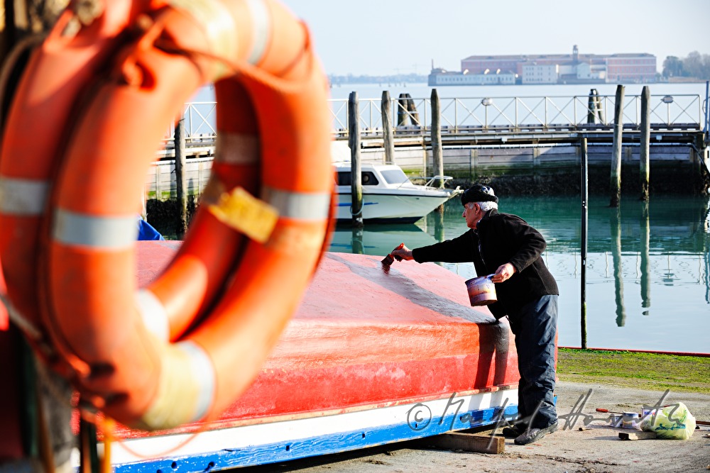 Maler streicht ein Boot bei einer Schiffswerft
