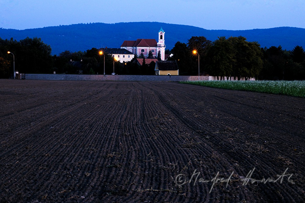 frisch gepflügtes Feld und Ortsansicht