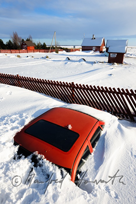eingeschneites Auto und Bootshäuser