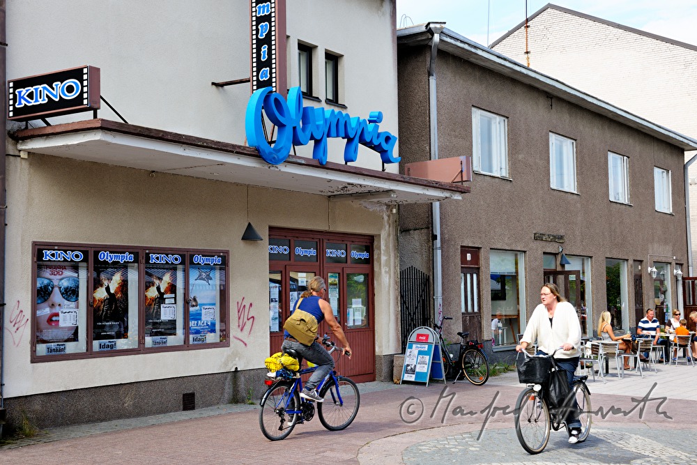 Radfahrer fahren am Kino vorbei