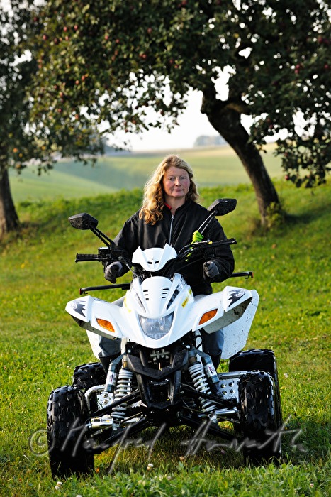 Bäuerin fährt mit ATV über die Weide