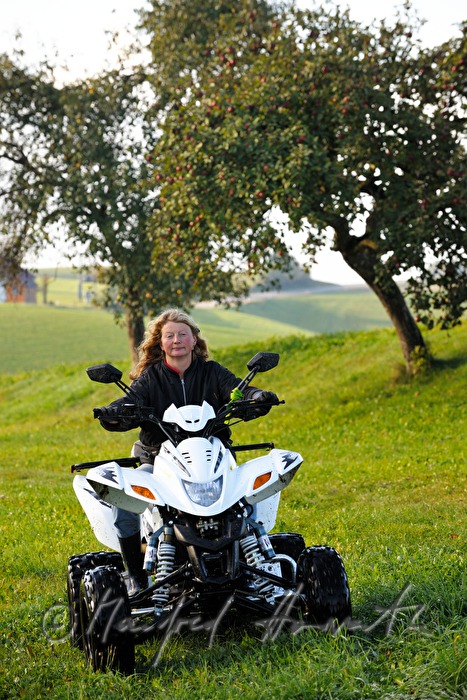 Bäuerin fährt mit ATV über die Weide