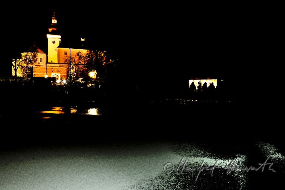 gefrorener Teich und Stand während des Adventmarktes