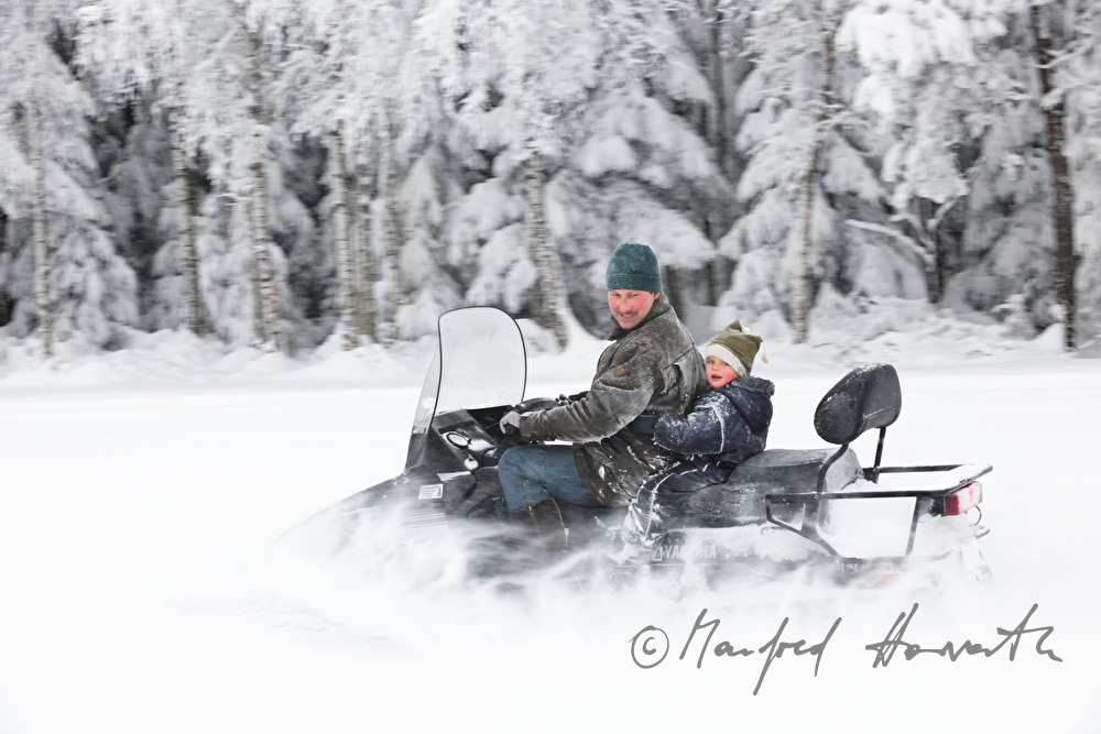 Vater mit Sohn unterwegs mit dem Motorschlitten