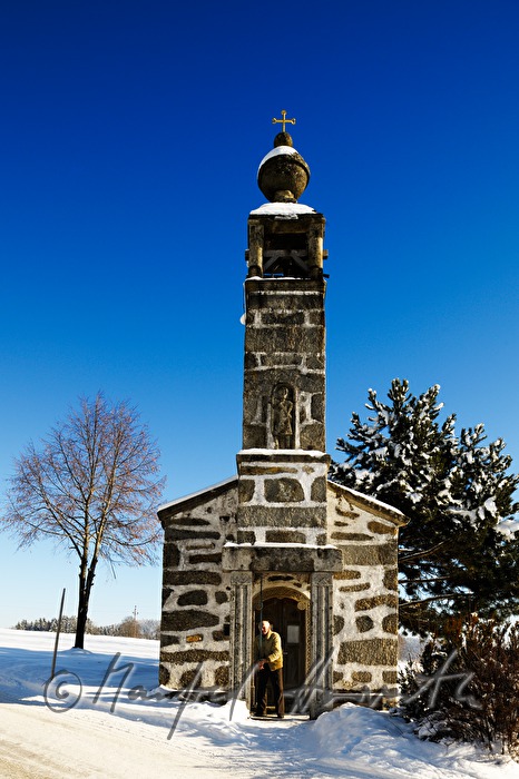 Mann läutet zu Mittag die Glocke der Dorfkapelle