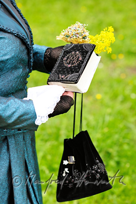 Frau in Mostviertler Tracht mit Handtasche und Gebetsbuch