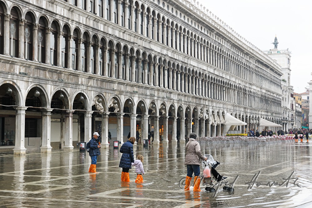 Familie überquert den Markusplatz bei Hochwasser