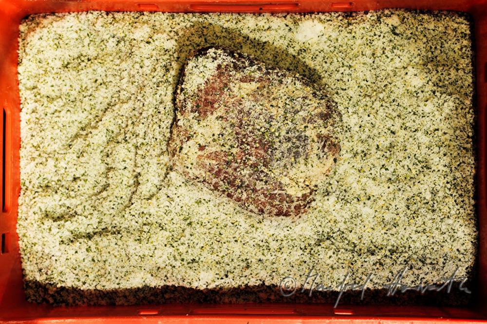Fleischermeister salzt Porcella Rohschinken ein